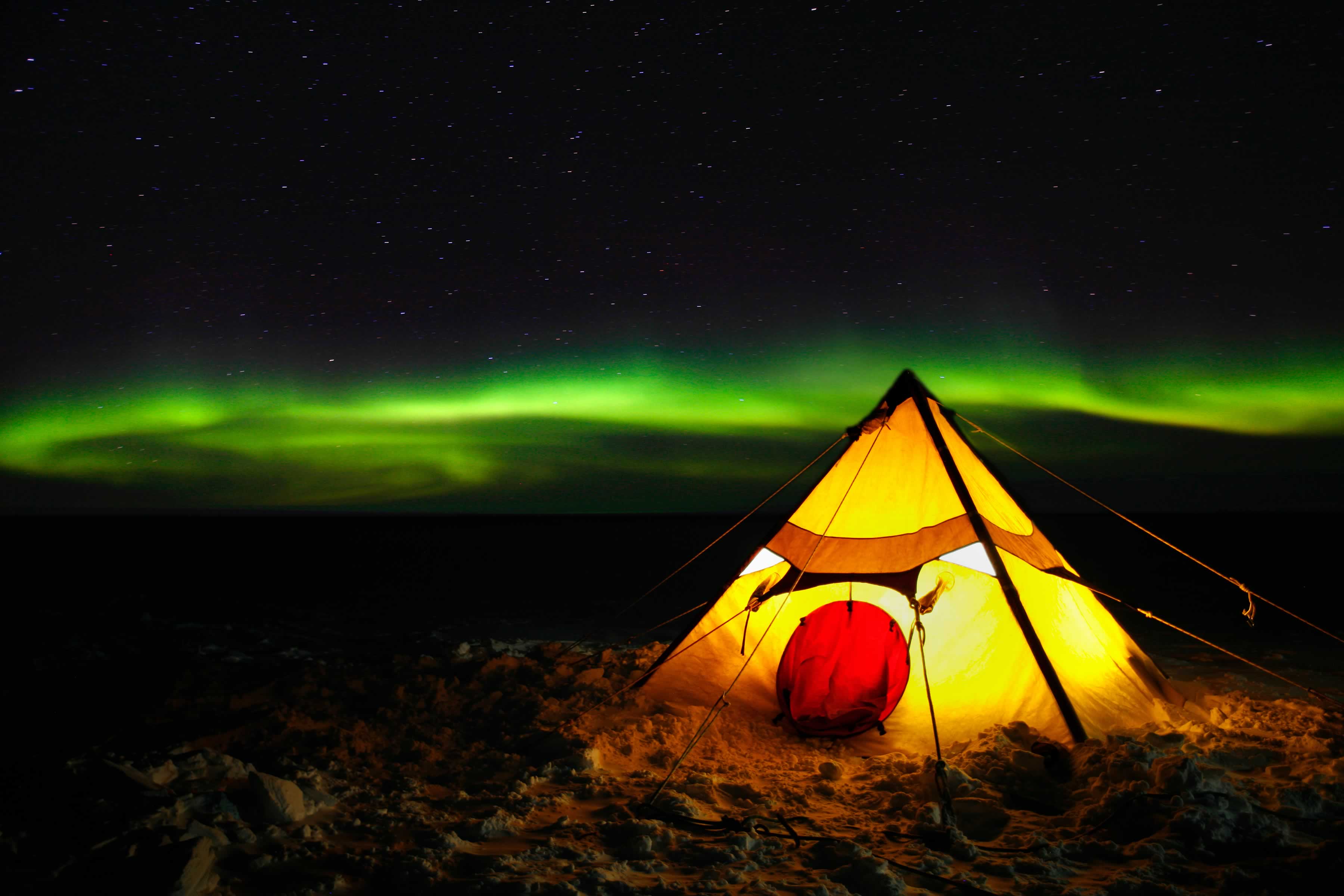 Light from within the tent contrasted against green aurora in the night sky. Photo: Christopher (Chris) Wilson.